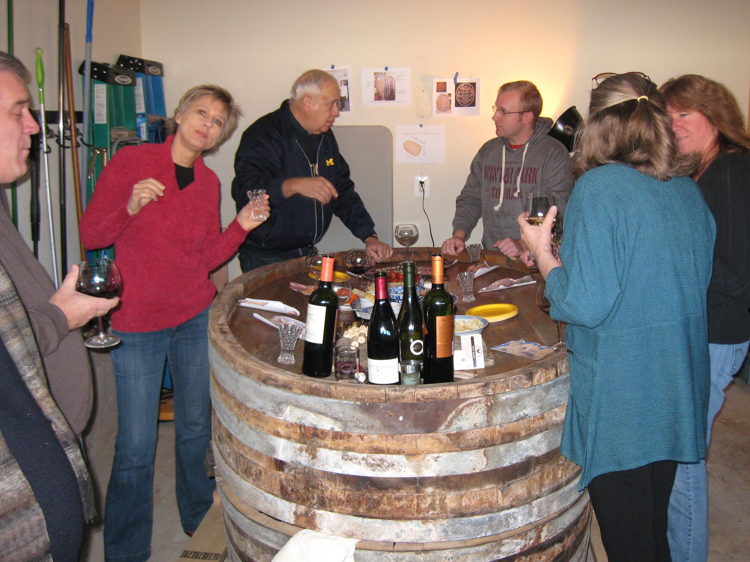 Neighbors gathered around the wine cask in the garage, sharing wine and food at a welcome home party