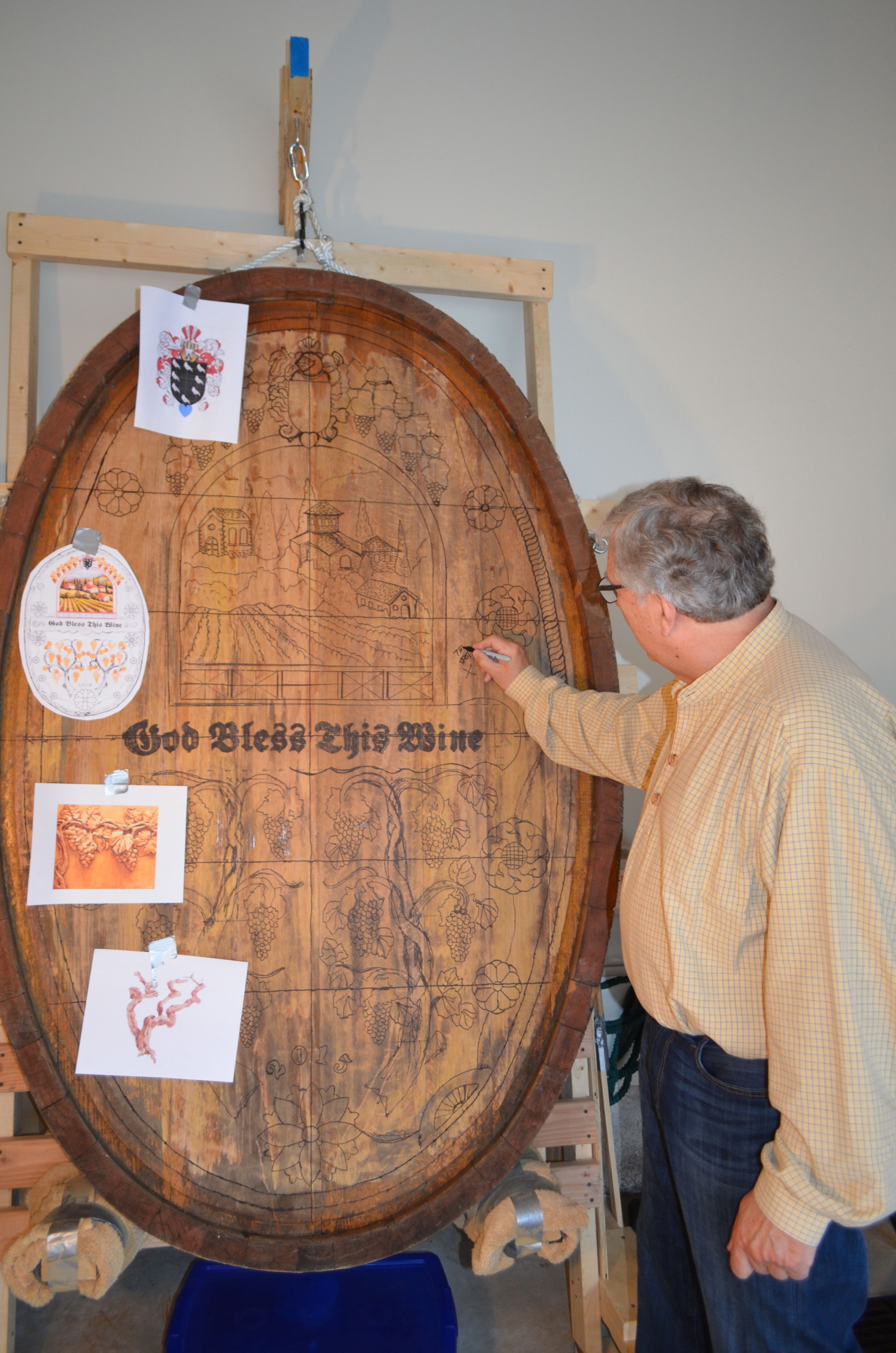 The artist drawing the vineyard design on the massive cask end mounted on the carving rack in the garage
